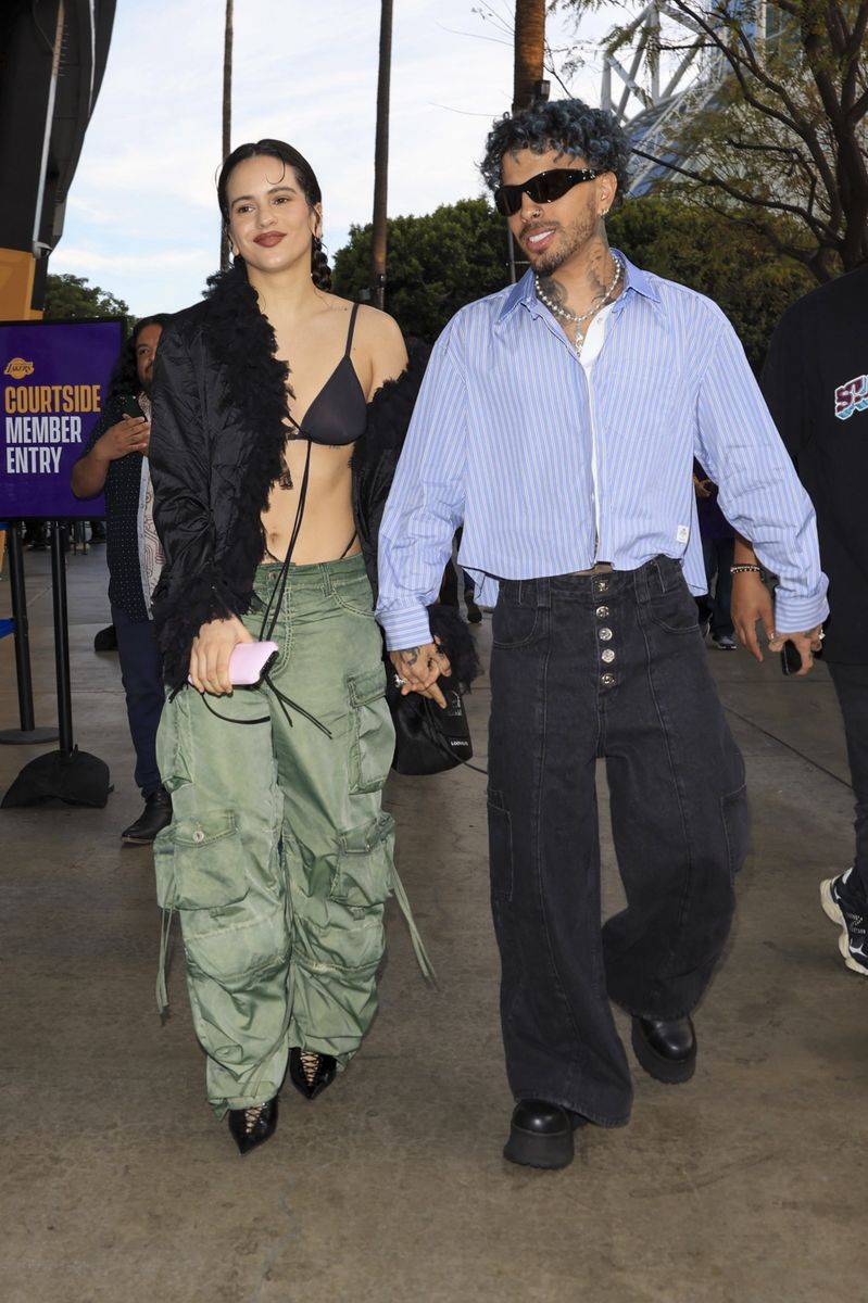 Rosalia and Rauw Alejandro hold hands, arriving at the Lakers game at the Crypto.com Arena in Los Angeles.