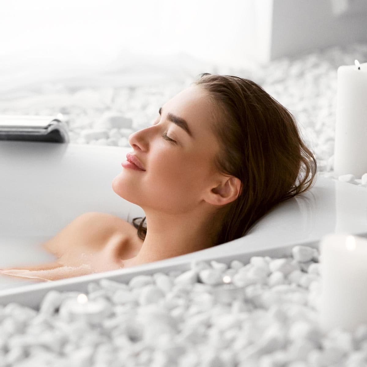 Mujer tomando un baño de agua caliente relajada y feliz