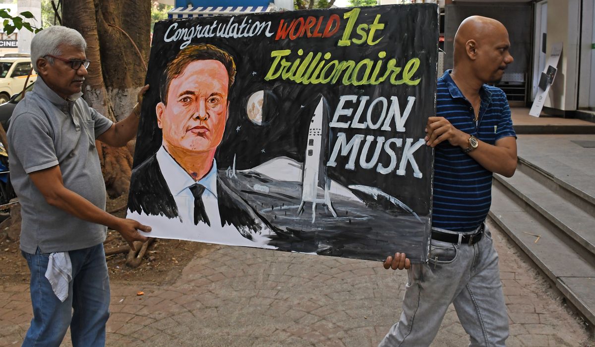 Teachers from Gurukul school of art carry back a painted poster congratulating businessman Elon Musk on becoming world's first trillionaire