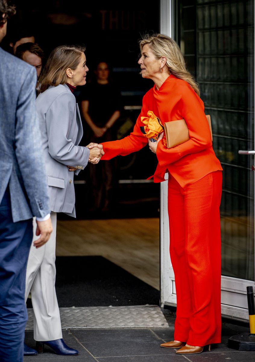 The royal paired her flowing wide-leg trousers and draped top with brown pointed-toe heels and a coordinating clutch.