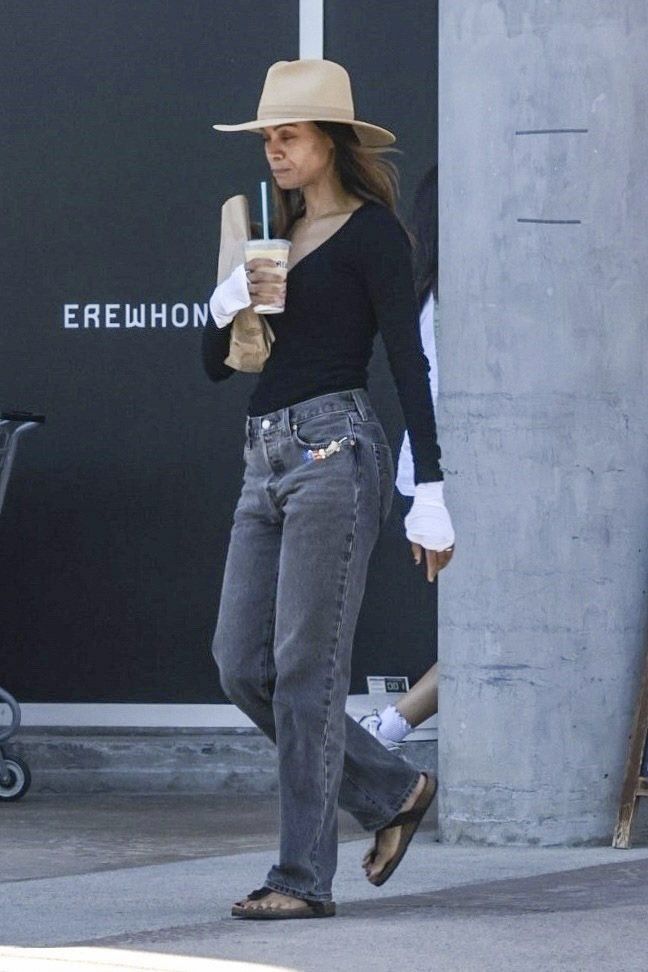  She wore a relaxed black long-sleeve top and grey straight-leg pants, complemented by white gloves and minimal accessories. 