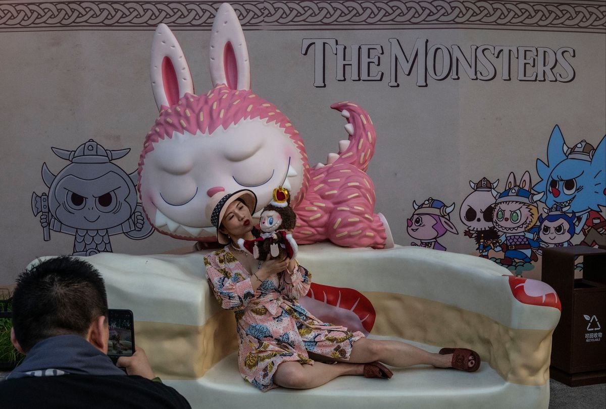 A Labubu fan holds a Labubu doll as she takes photos in front of the Mokoko character from  Pop Mart's hugely popular dolls series.