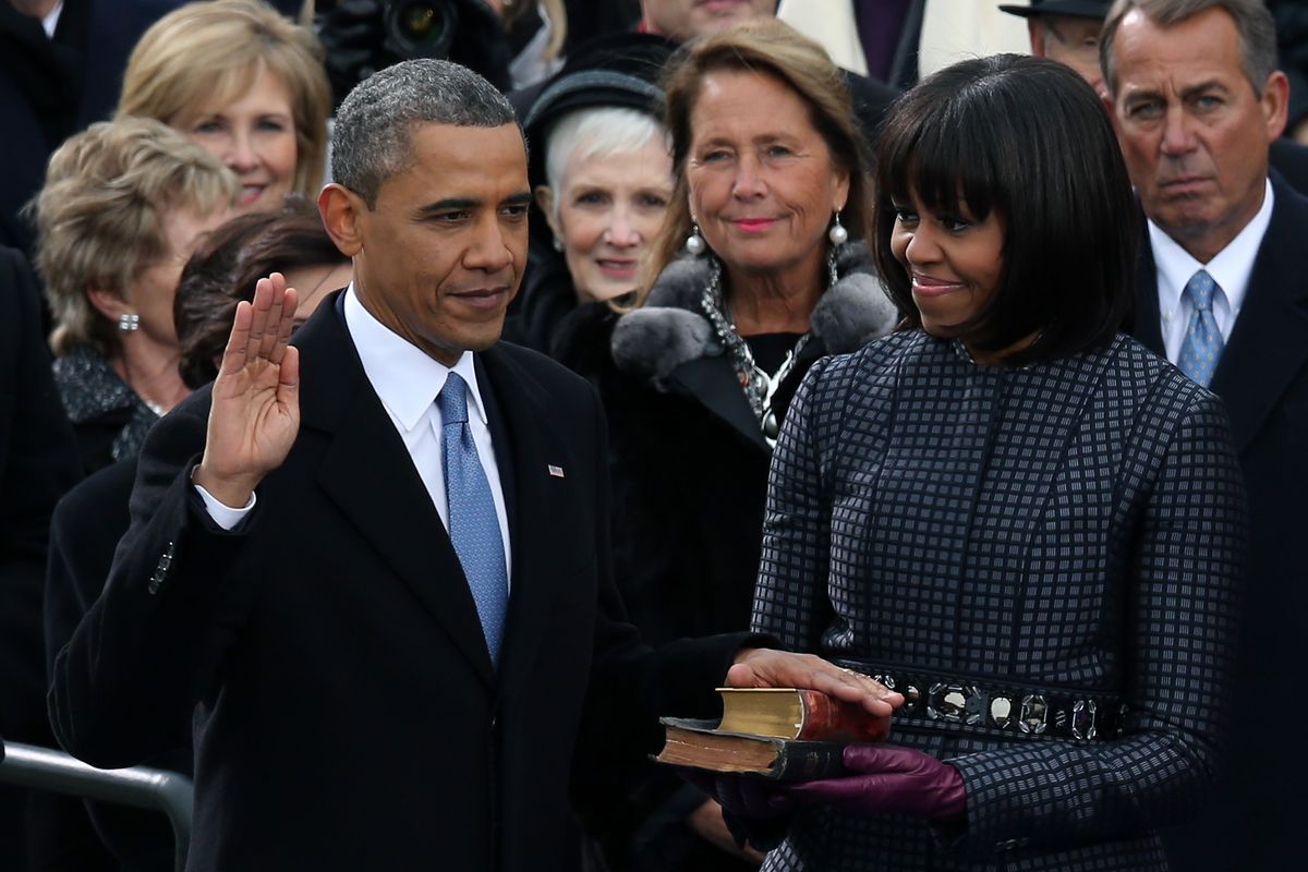 WASHINGTON, DC - JANUARY 21:  U.S. President Barack Obama is sworn in during the public ceremony as First lady Michelle Obama looks on during the presidential inauguration on the West Front of the U.S. Capitol January 21, 2013 in Washington, DC.   Barack Obama was re-elected for a second term as President of the United States.  (Photo by Alex Wong/Getty Images) 