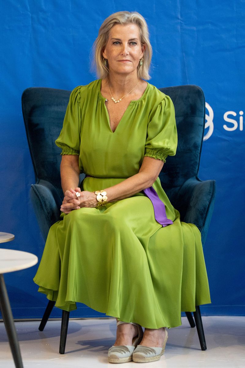 The Duchess of Edinburgh steps out in Lusaka wearing a vibrant lime-green Soler midi dress with a contrasting purple sash.