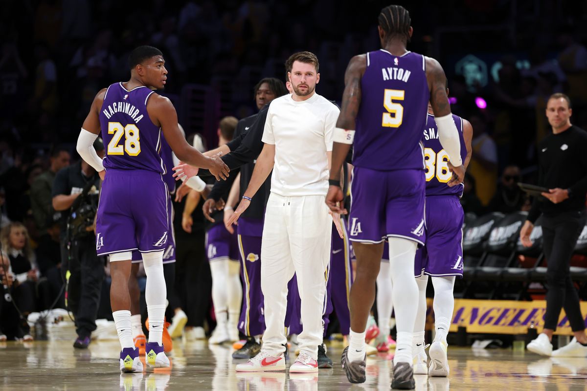 Luka Doncic #77 of the Los Angeles Lakers greets Deandre Ayton #5 during a timeout during the second quarter against the Houston Rockets