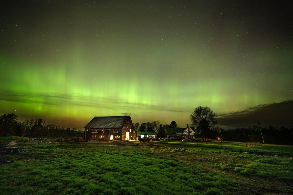 The northern lights fill the sky with green ribbons of electrically charged particles over the barn and pastures at Greaney's Turkey Farm in Mercer, Maine.
