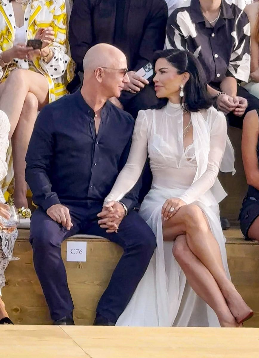 Jeff Bezos and  Lauren Sanchez look in love as they hold hands, sitting in the front row at the Dolce & Gabbana fashion show in Sardinia. 
