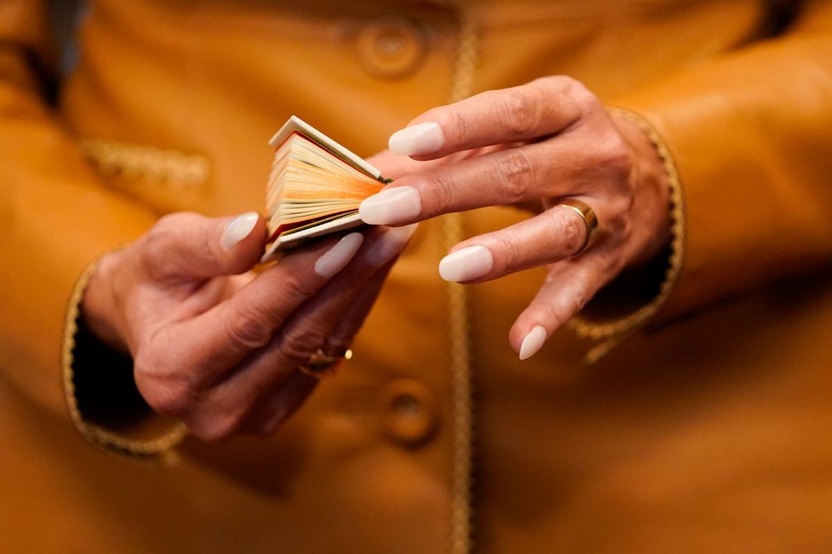 Melania holding on to a miniature antique book on her tour through the Royal Library