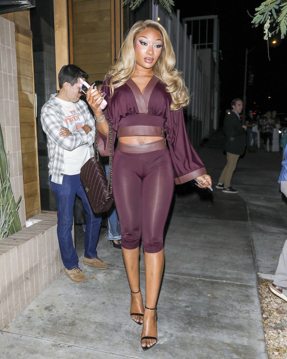 Megan Thee Stallion stepped out in Los Angeles wearing a burgundy coordinated ensemble featuring a cropped top, flowing sleeves, and fitted capri pants.