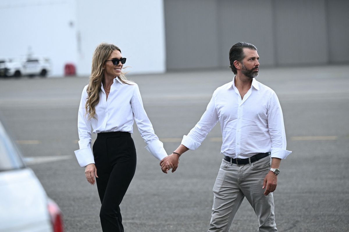 Donald Trump Jr. and his girlfriend Bettina Anderson walk on the tarmac as they await the arrival of President Donald Trump and First Lady Melania Trump.