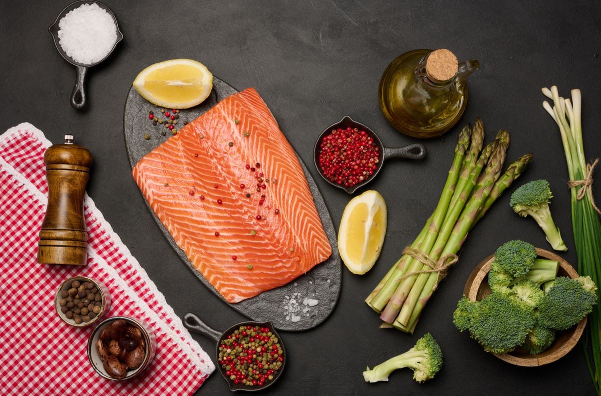 Raw piece of trout on a black board and spices, top view