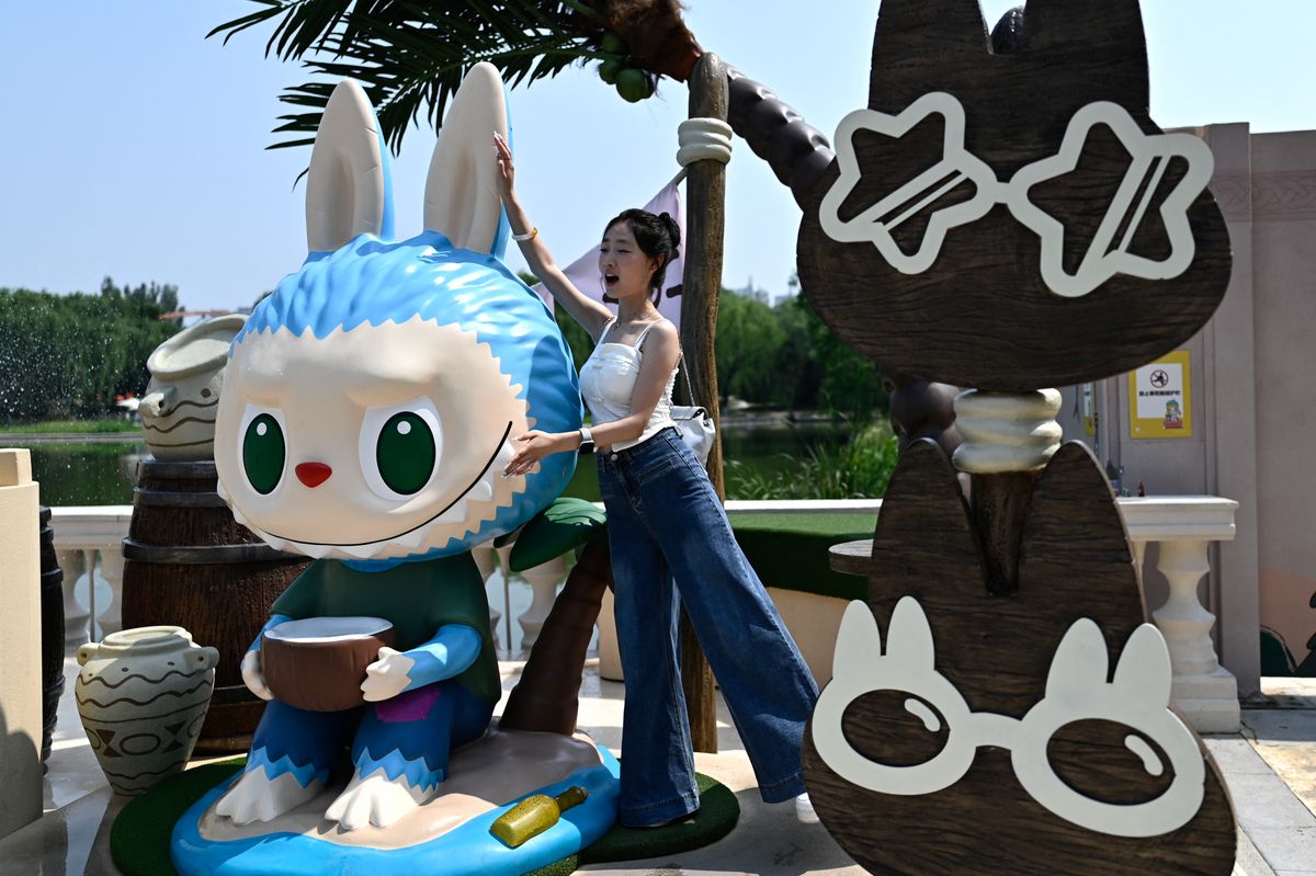 Visitors strike playful poses with Labubu towering behind them.
