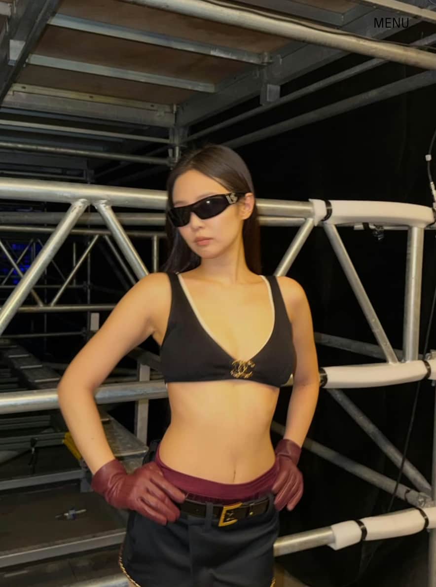 In Singapore, Jennie stepped out in a burgundy leather bomber featuring gold hardware. Underneath, she wore a layered black bra, paired with a black mini skirt and Y2K glasses.
