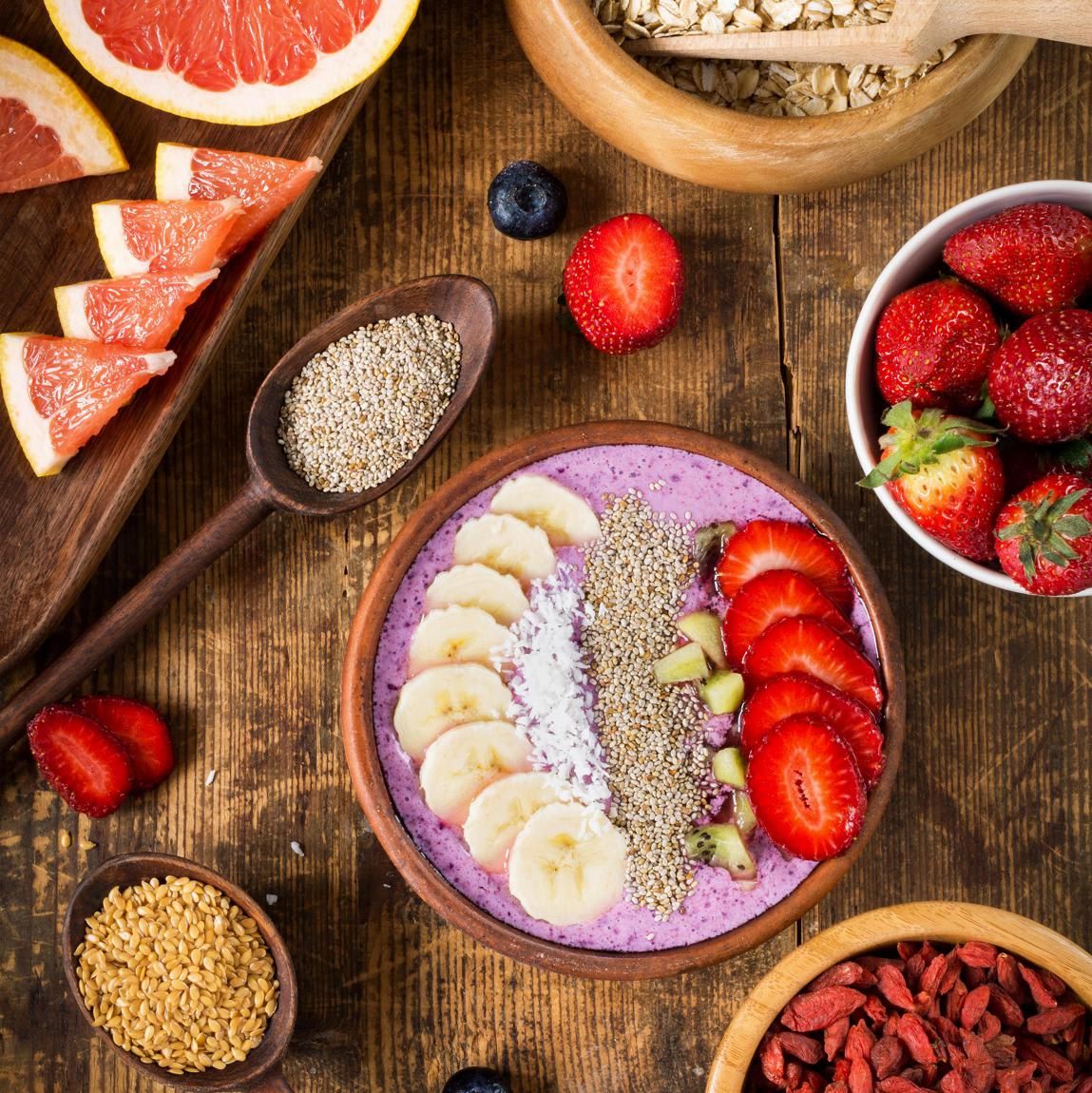 Acai berry smoothie bowl topped with chia seeds, coconut flakes, banana, strawberries and kiwi with variety of superfoods