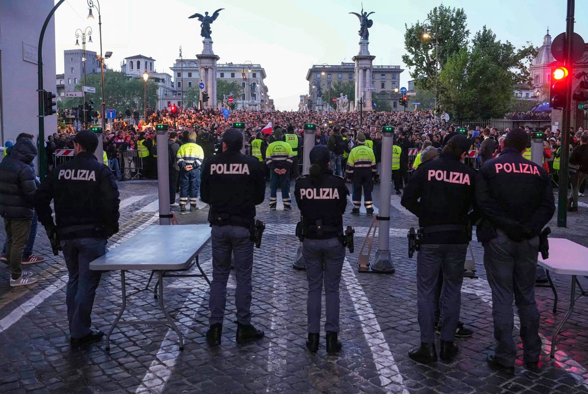 Police officers stand guard as people queue on the street ahead of late Pope Francis' funeral near the Vatican, in Rome on April 26, 2025.