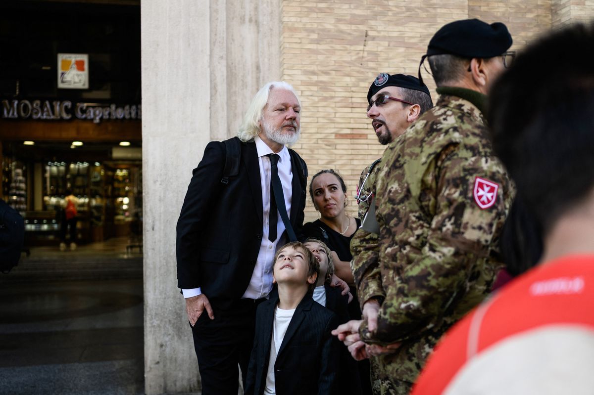 WikiLeaks founder Julian Assange (L) speaks with a member of the military forces as he attends the late Pope Francis' funeral ceremony with his wife Stella and children Gabriel and Max, at Via della Conciliazione by St Peter's Square in The Vatican on April 26, 2025.     