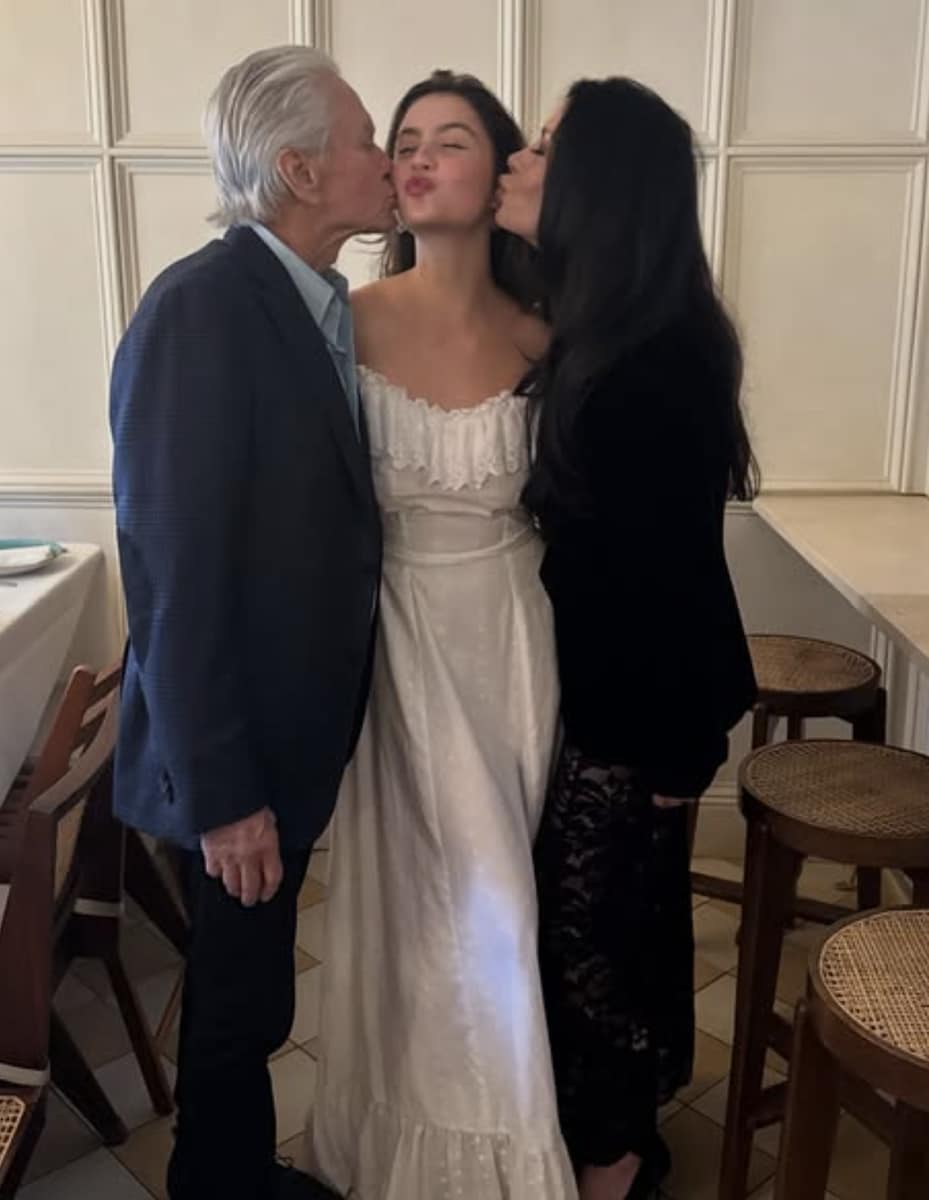 Michael Douglas and Catherine Zeta-Jones kissing their daughter