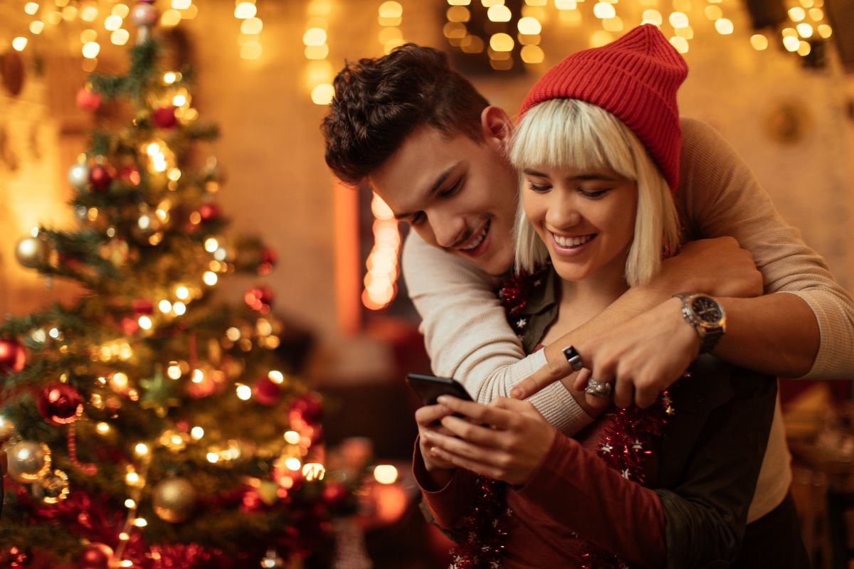 Couple hugging and using smartphone at New Year's party