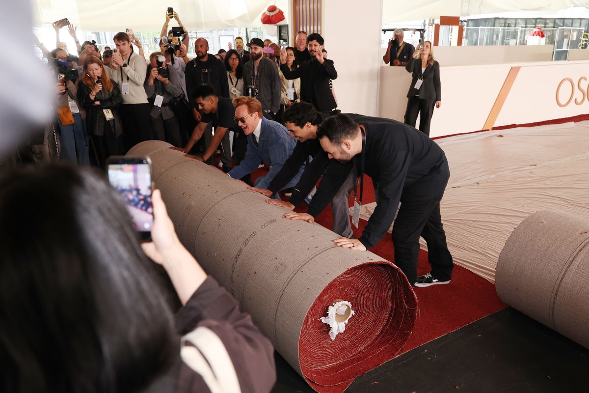 Conan O'Brien helps the crew during the 98th Oscars red carpet roll out at Ovation Hollywood on March 11, 2026 in Hollywood, California.