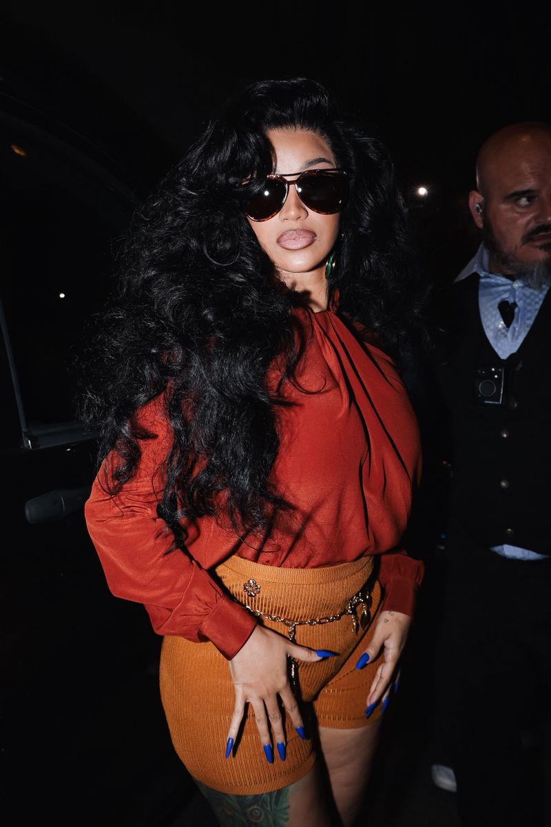 Cardi paired a rust-red blouse with tiny burnt-orange knit shorts and voluminous curls for a Versace party celebrating Vogue World: Milano.