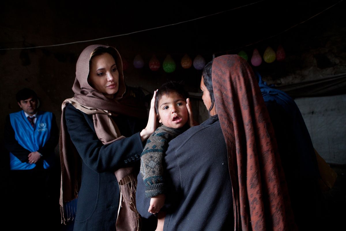 Angelina Jolie, meets with Khanum Gul, 35, a mother of 8, and her youngest son, Samir at their makeshift home at Tamil Mill Bus site February 2011, in Kabul city, Afghanistan