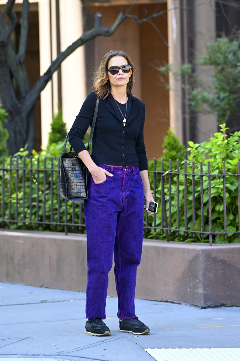 Katie Holmes stepped out in vibrant purple jeans paired with a fitted black cardigan and sporty sneakers.