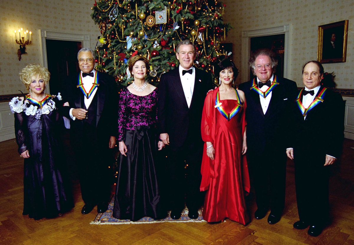 (From L to R) Actress Elizabeth Taylor, actor James Earl Jones, first lady Laura Bush, U.S. President George W. Bush, actress Chita Rivera, conductor James Levine and singer Paul Simon pose for a picture after the Kennedy Center Honors of 2002 recipients were honored at the White House on December 8, 2002 in Washington, D.C. Each year, the John F. Kennedy Center for the Performing Arts honors a select number of artists for lifetime achievements and their influence upon American culture.