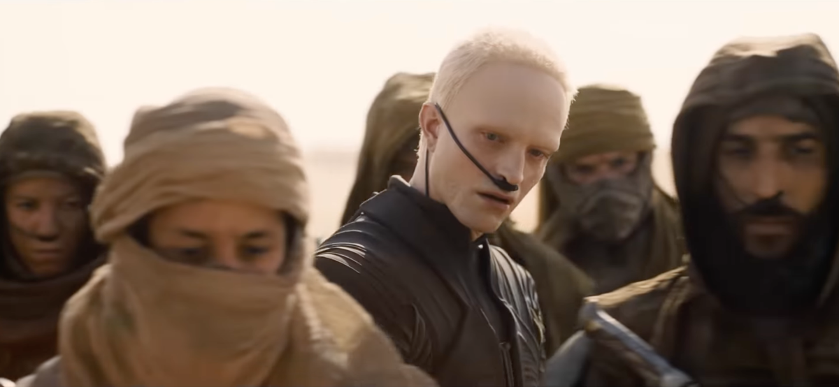 His look, bleached eyebrows, and buzzed blonde hair, is already drawing attention, but it’s the ambiguity of his character that stands out