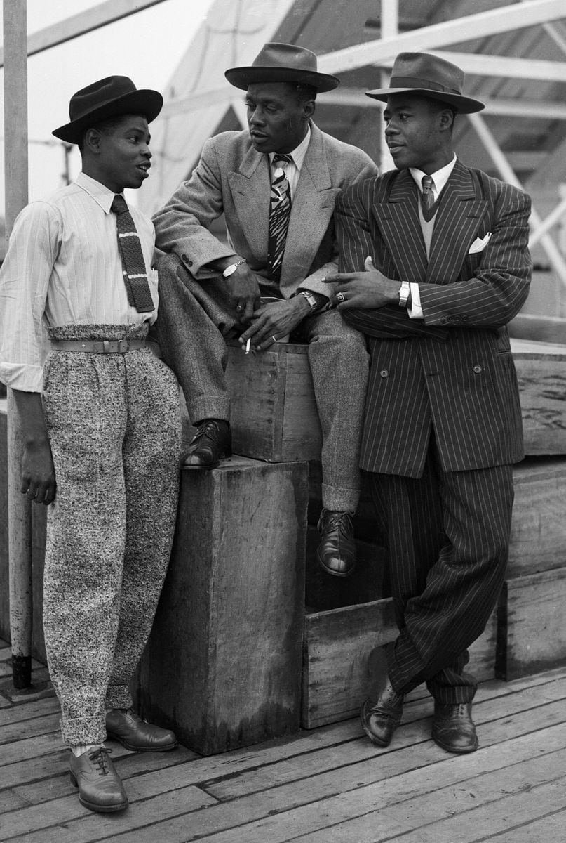 Three Jamaican immigrants (left to right) John Hazel, a 21-year-old boxer, Harold Wilmot, 32, and John Richards, a 22-year-old carpenter, arriving at Tilbury on board the ex-troopship 'Empire Windrush', smartly dressed in zoot suits and trilby hats. (Photo by Douglas Miller/Keystone/Hulton Archive/Getty Images)