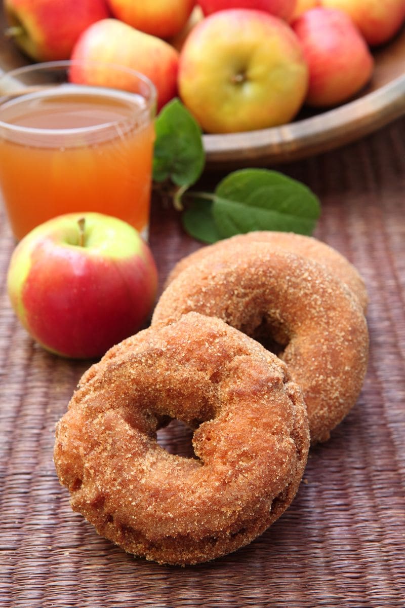 Apple Cider Doughnuts rolled in cinnamon sugar, served with a glass of apple cider.  Apple Cider Doughnuts are an autumn specialty. They are a cake doughnut made with apple cider in the batter.