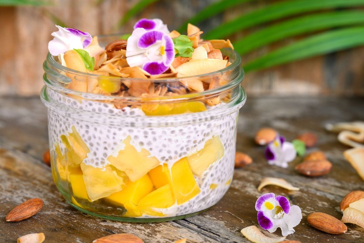 Chia seed pudding in a glass jar loaded with fruits and toasted coconut.