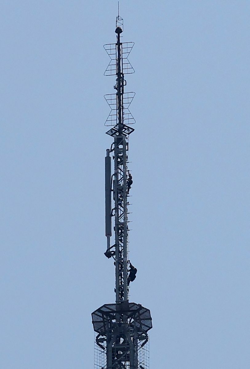 Two people climb on the spire of the Empire State Building in New York on July 1, 2026.