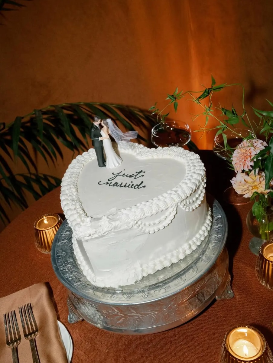The newlyweds celebrated with a heart-shaped cake decorated with white piping.