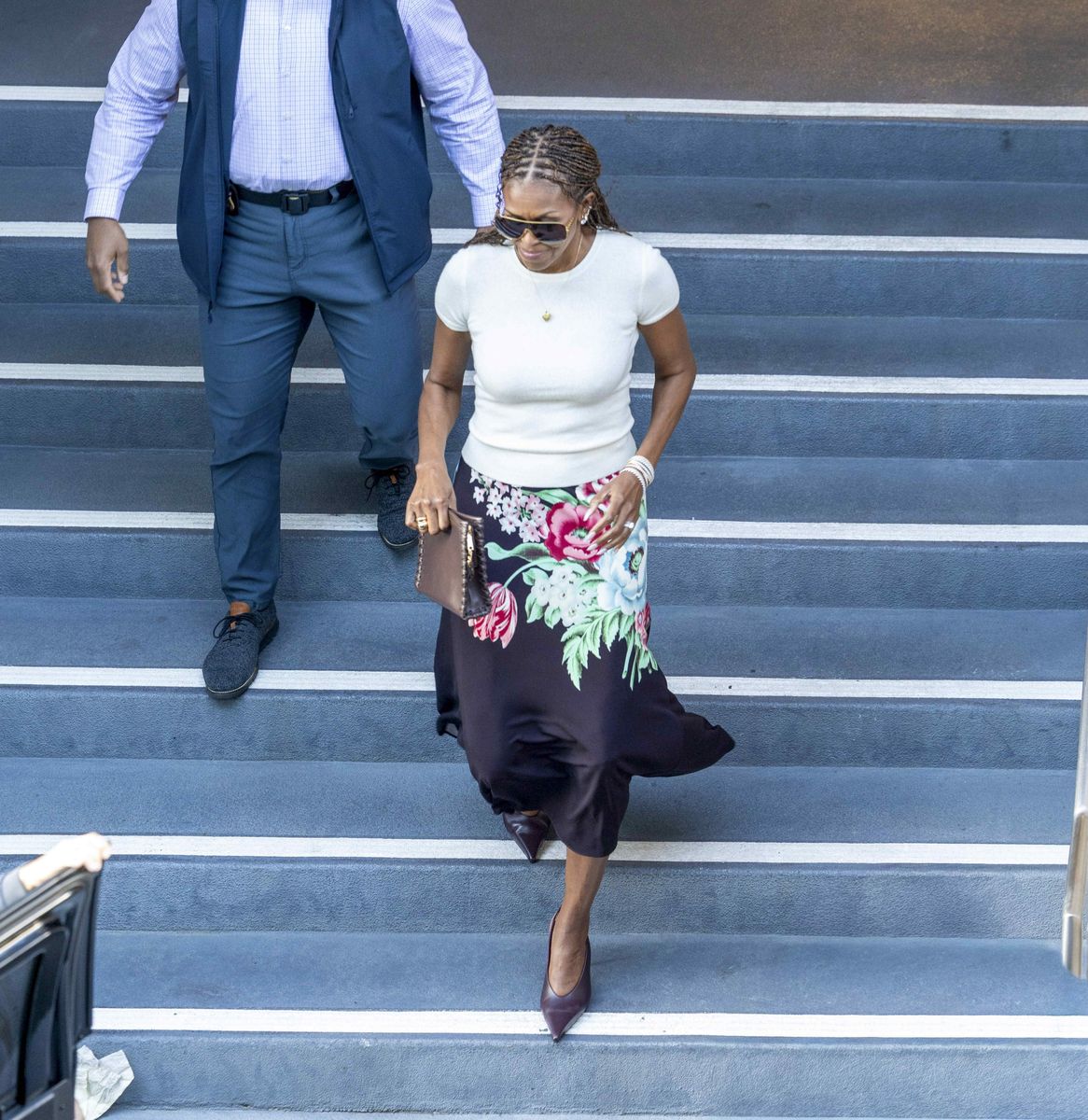 Michelle Obama is seen exiting CNN headquarters following a meeting, wearing a printed jersey midi skirt paired with a fitted white top.