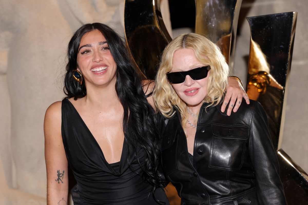 
Madonna attended the Saint Laurent Spring-Summer 2026 show during Paris Fashion Week, posing at the photocall with her daughter Lourdes Leon and Akeem Morris. Madonna wore an all-black outfit featuring a fitted leather jacket with a plunging neckline, a sheer lace skirt revealing lingerie, patent pointed heels, diamond necklaces, dark sunglasses, and a large furry brown handbag. Lourdes Leon matched in a coordinated black look, while Akeem Morris appeared in a dark-toned outfit in line with the evening aesthetic.
***
Madonna asistió al desfile Saint Laurent Primavera-Verano 2026 durante la Semana de la Moda de París y posó en el photocall junto a su hija Lourdes Leon y Akeem Morris. Madonna llevó un conjunto totalmente negro con chaqueta de cuero ajustada y escote pronunciado, falda de encaje transparente que dejaba ver la lencería, tacones de charol puntiagudos, collares de diamantes, gafas de sol oscuras y un bolso marrón peludo de gran tamaño. Lourdes Leon acompañó con un look negro coordinado, mientras que Akeem Morris apareció con un estilismo en tonos oscuros acorde a la estética nocturna.