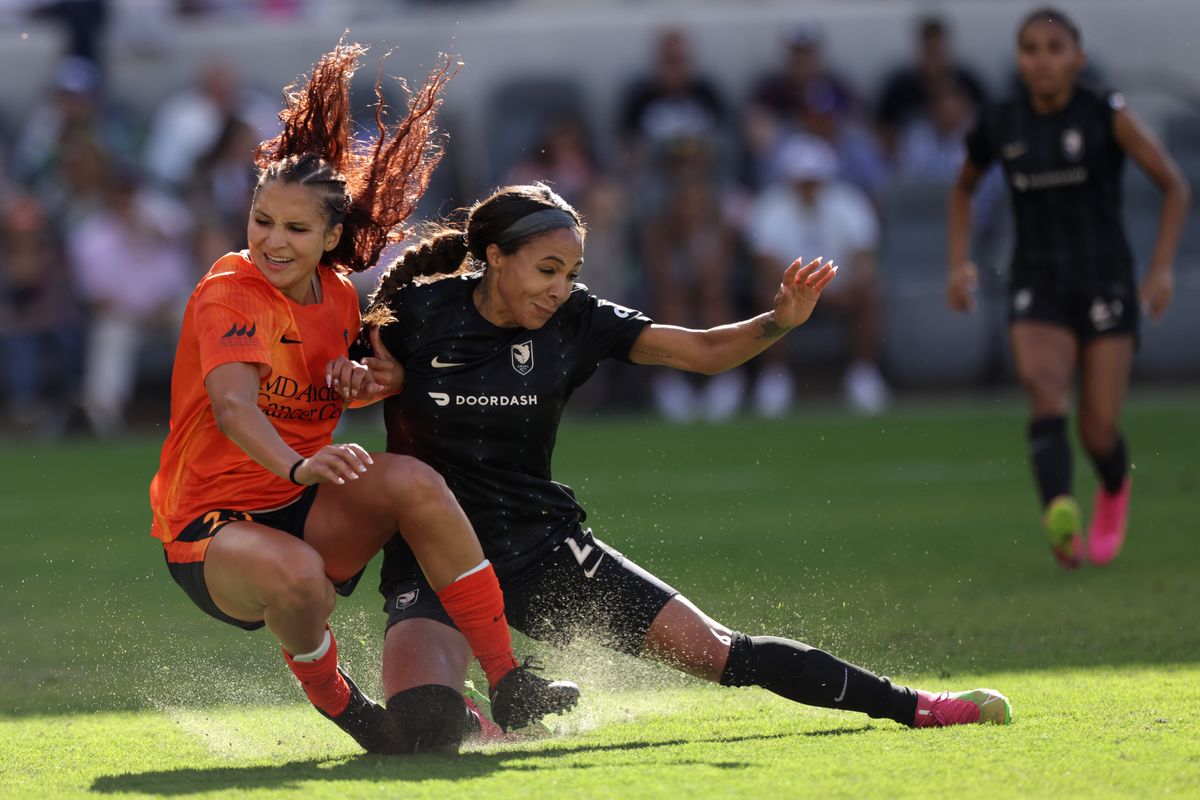 LOS ANGELES, CALIFORNIA - JUNE 25: Ally Prisock #23 of the Houston Dash and Sydney Leroux #2 of Angel City FC fall after jumping for a header during the first half of a game at BMO Stadium on June 25, 2023 in Los Angeles, California. (Photo by Katharine Lotze/Getty Images)