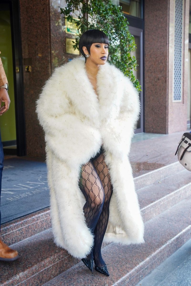 Cardi B made a dramatic arrival for the Gucci fashion show in Milan, wearing an oversized white faux-fur coat with sheer monogram tights and a sleek pixie cut.