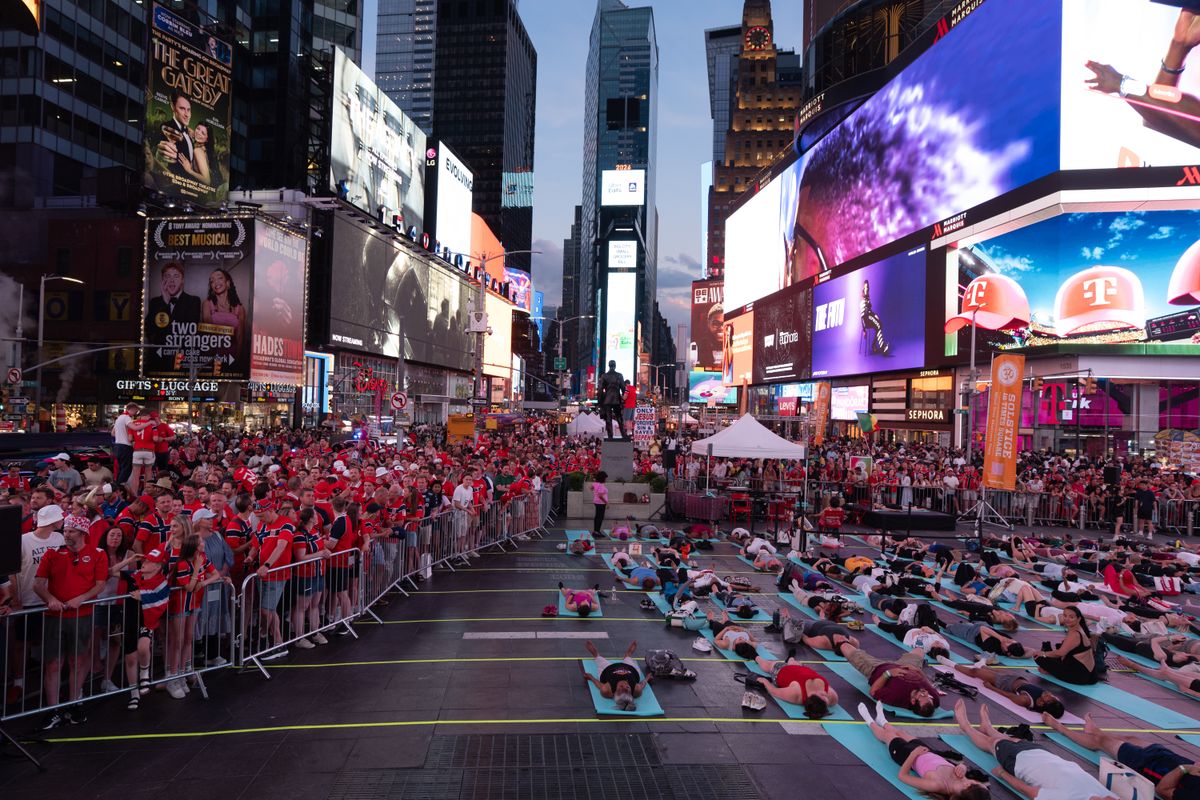 A group does yoga as Norwegian national football team supporters gather on the iconic red steps in Times Square