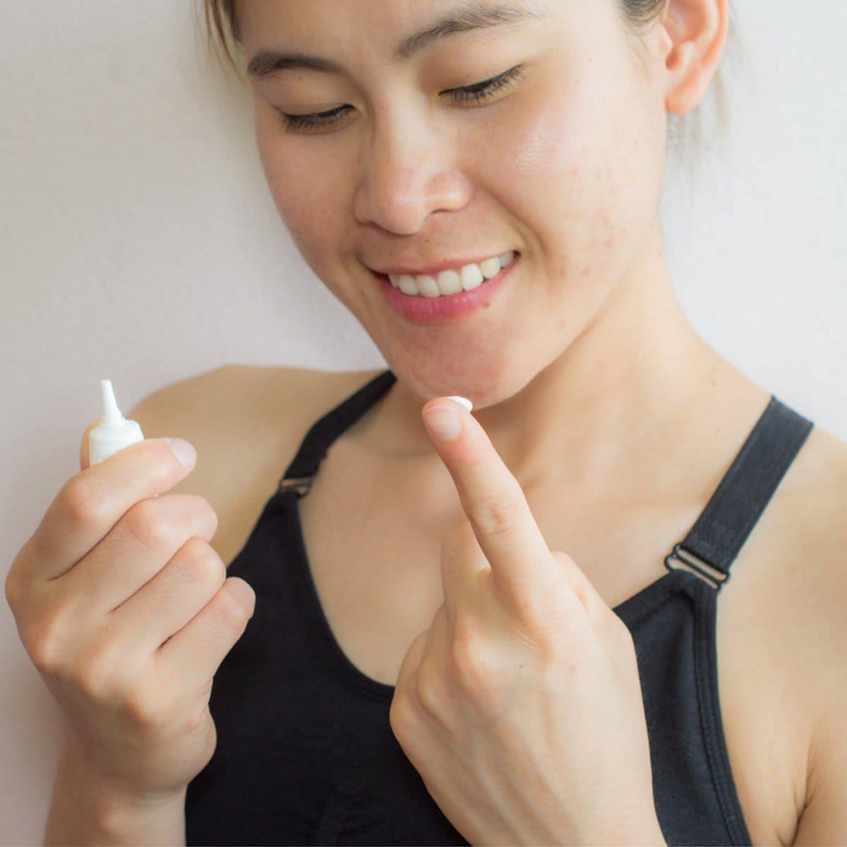 Shot of woman preparing for applying acne cream for solve her problem skin