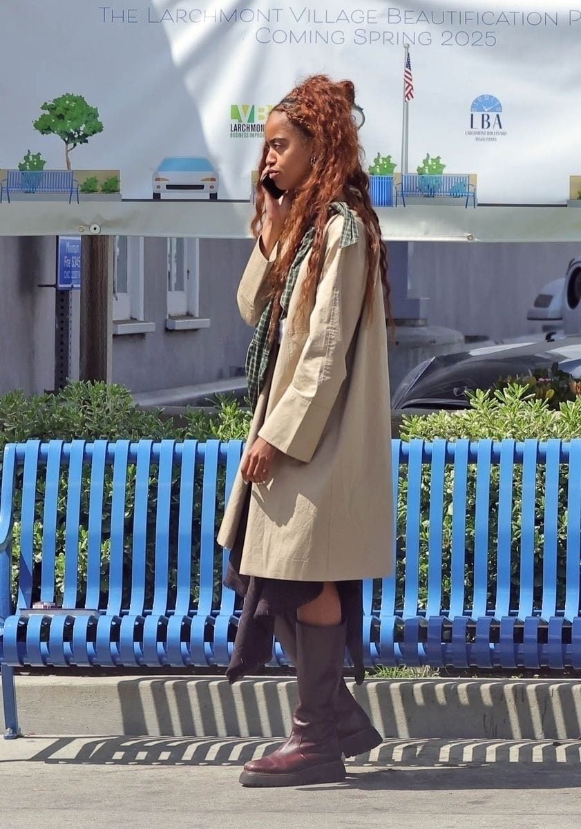 

Malia Obama was seen walking down the street in a stylish beige trench coat and knee-high brown boots. She accessorized with a green plaid scarf tied around her waist while chatting on the phone. Her look was completed with a white t-shirt and dark skirt, exuding effortless elegance.****

Malia Obama fue vista caminando por la calle con un elegante abrigo trench beige y botas marrones hasta la rodilla. Complementó su atuendo con una bufanda de cuadros verdes atada a la cintura mientras hablaba por teléfono. Su look se completó con una camiseta blanca y una falda oscura, irradiando elegancia sin esfuerzo.