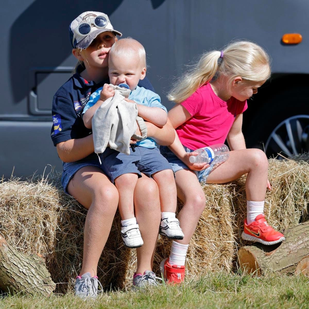 Taking a break! Mia sweetly held her brother on her lap while at Gatcombe Park. Sister Lena joined the duo on a bale hay.