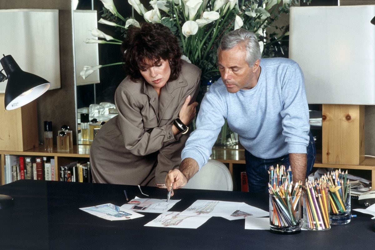 Italian fashion designer Giorgio Armani showing some sketches to American actress Linda Gray. 1983 (Photo by Angelo Deligio/Mondadori via Getty Images)