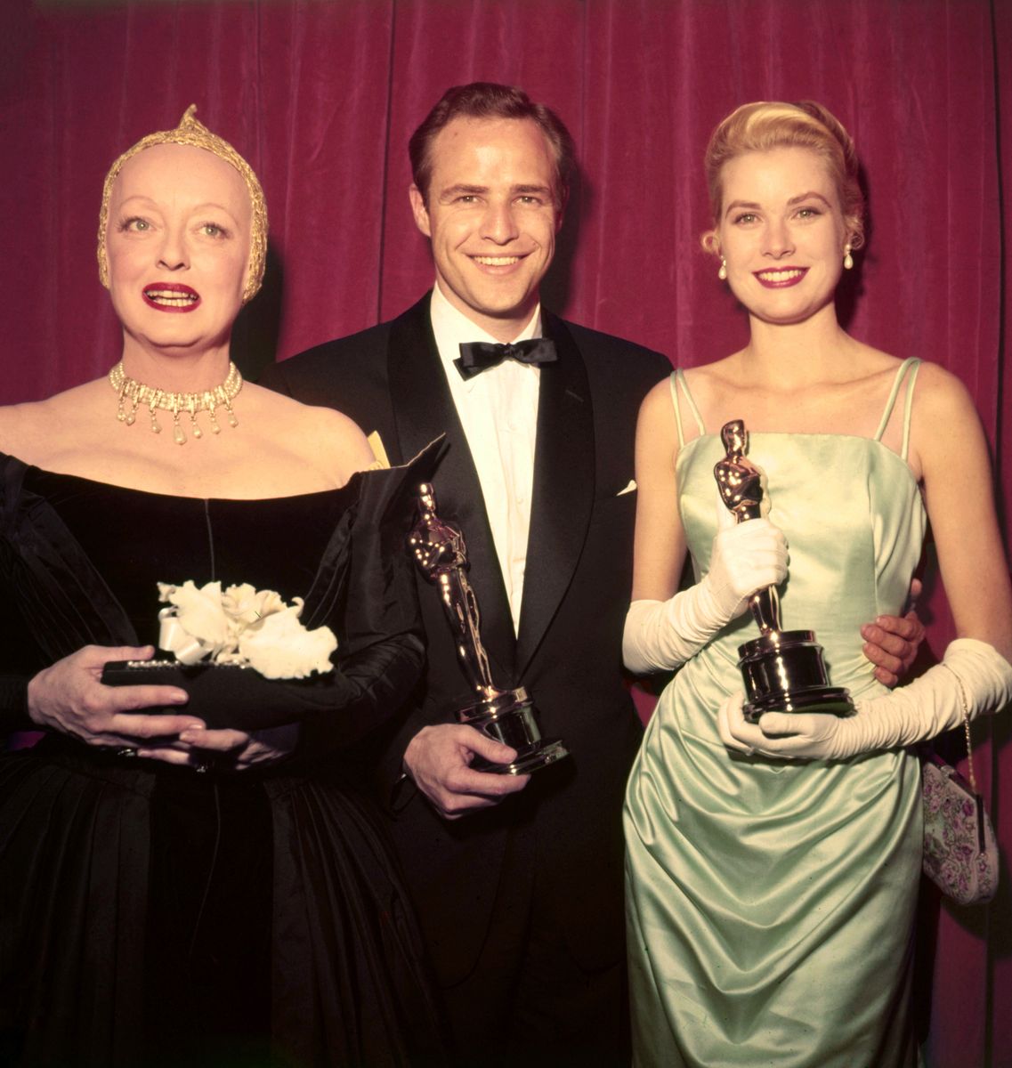 Marlon Brando and Grace Kelly holding the Academy Award Oscar statuettes won for 'On the Waterfront' and 'The Country Girl', respectively, at the 27th  Academy Awards, with presenter Bette Davis standing beside them, 30th March 1955. 