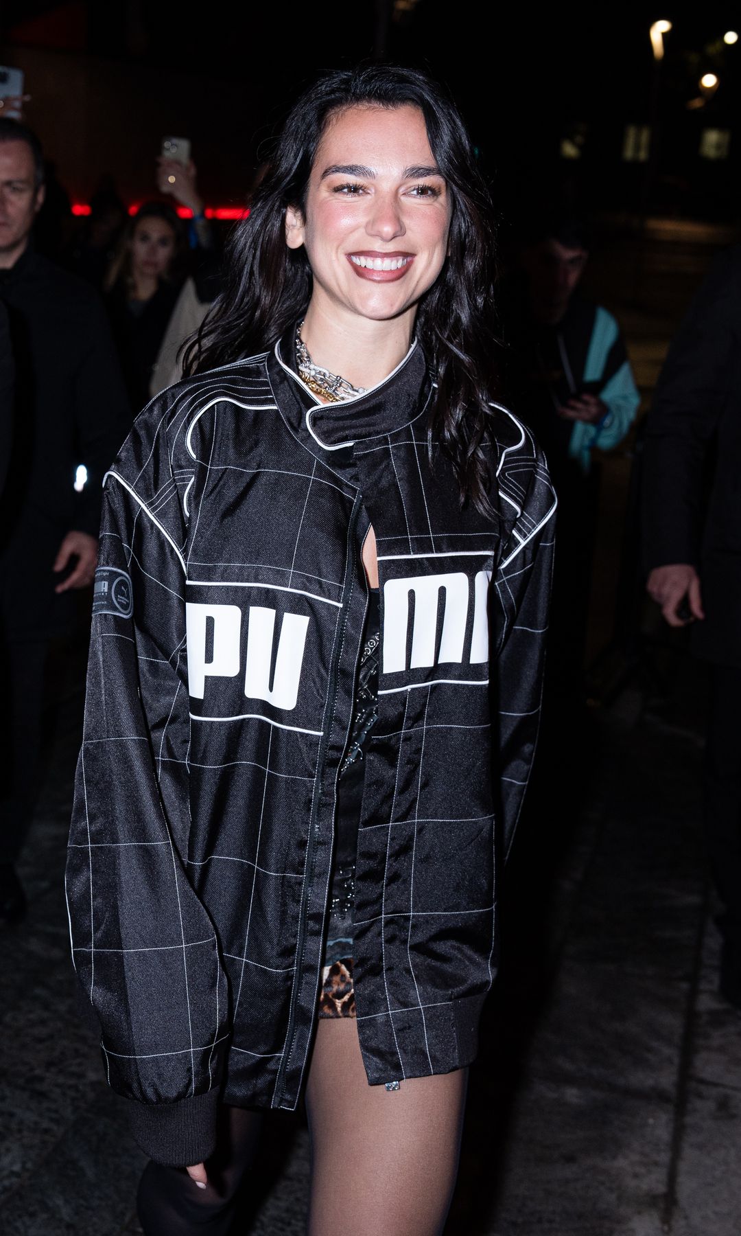 Dua Lipa attends the PUMA Speedcat Launch Celebration wearing an oversized sports jacket, she completes the look with her hair down and light makeup.