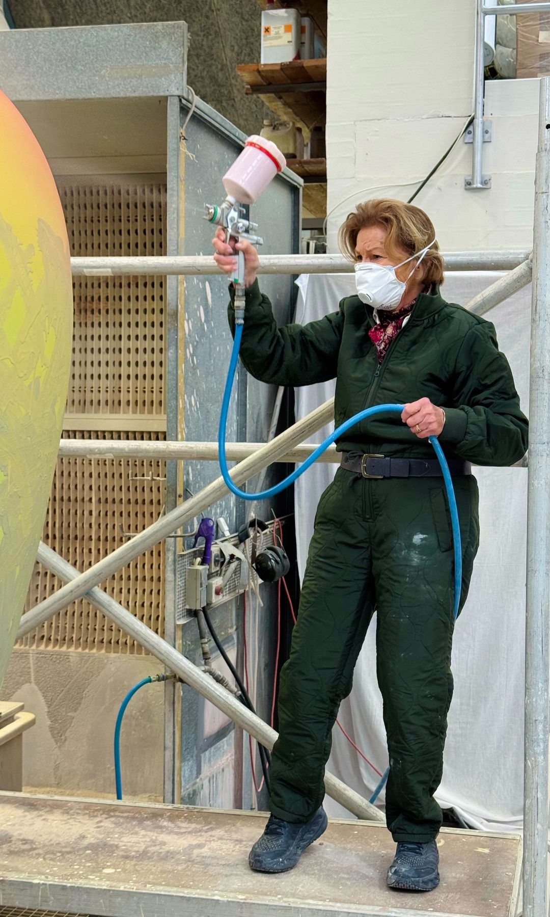 The Queen looked prepared as she wielded a paint brush and protected herself from the fumes with a face mask