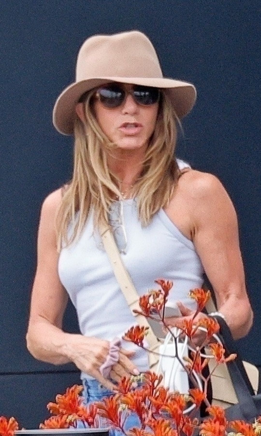 Jennifer Aniston shows off her toned arms as she returns from a romantic getaway to Spain with her new beau, Jim Curtis. 