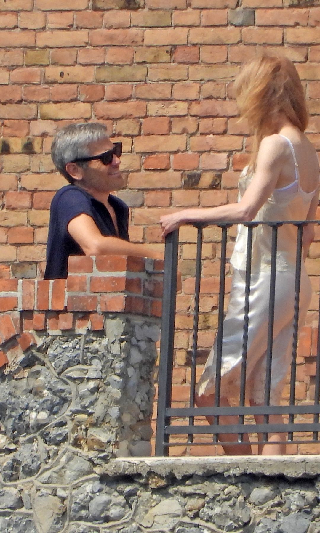 Reinstein leaned against the terrace wall while the two chatted from opposite sides of the balcony