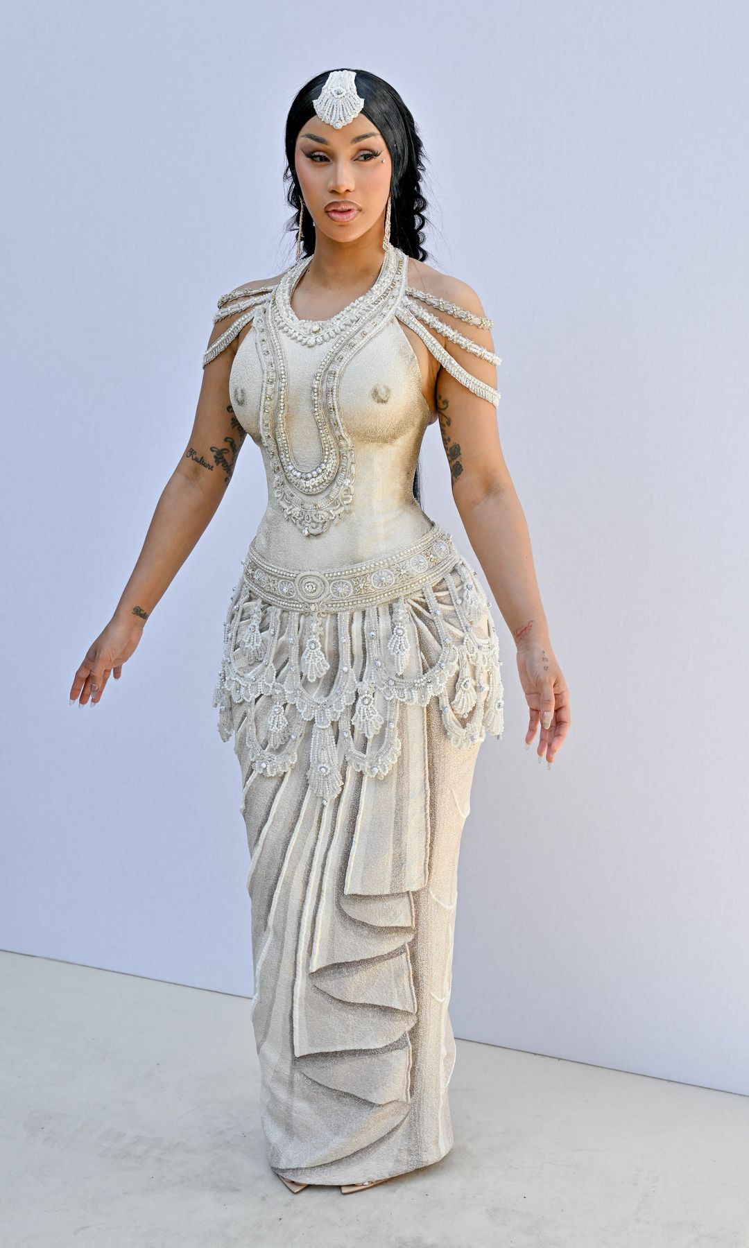 Cardi B turned heads in a cream embroidered dress paired with strappy heels, delivering an elegant yet eye-catching look that reflected her signature glamorous style.