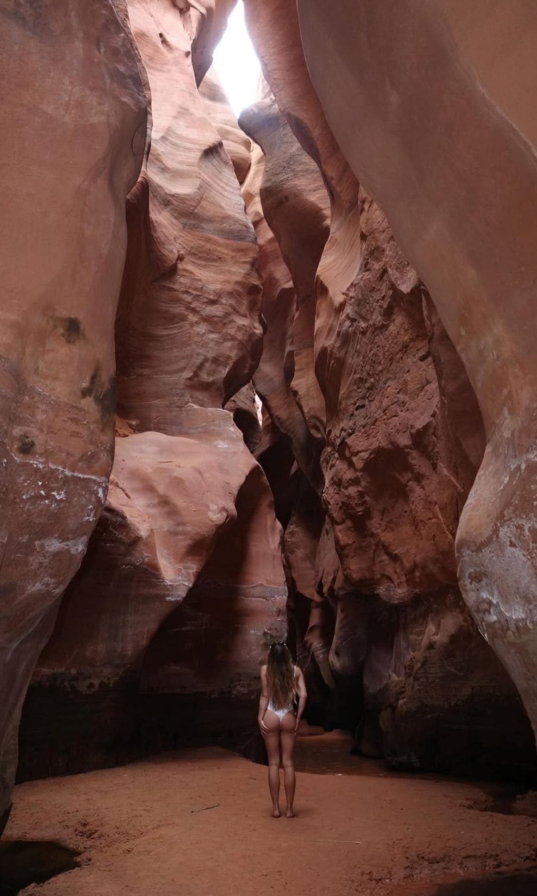 With a wandering spirit, Sydney explores the canyon in a white swimsuit, taking in the natural beauty.