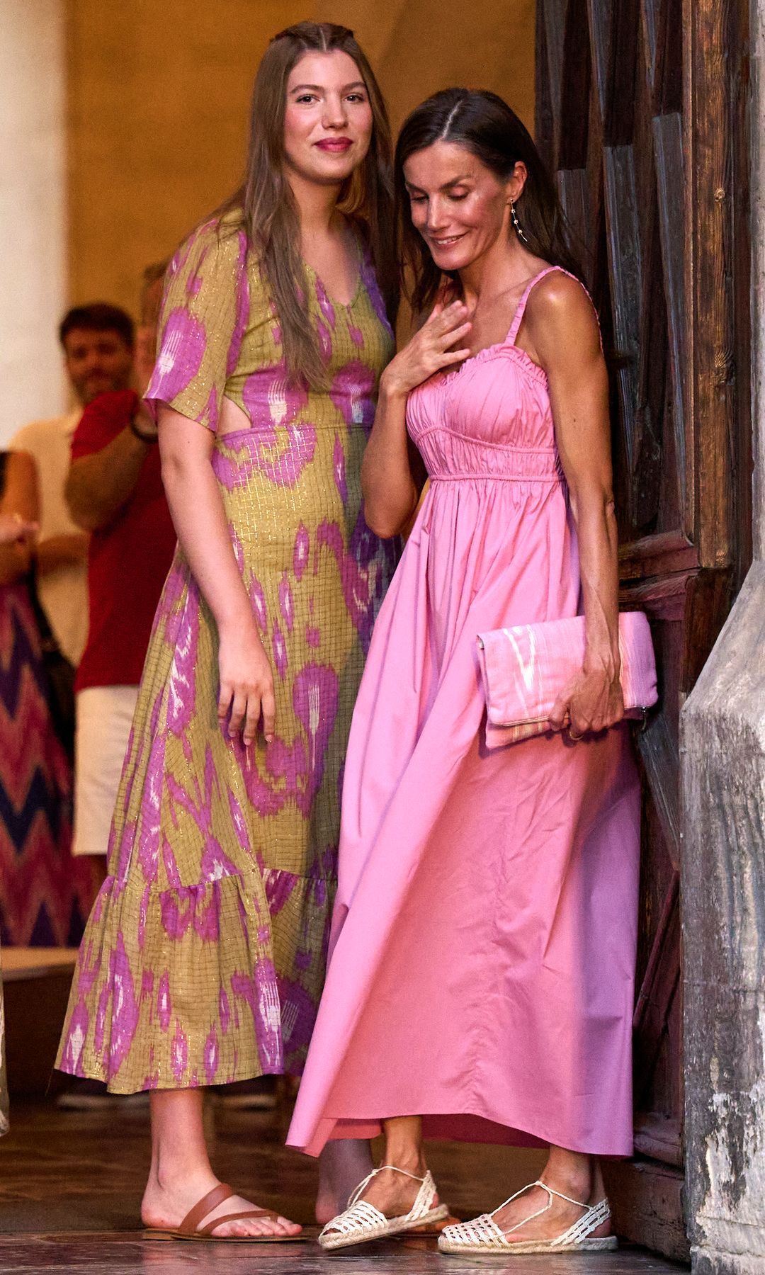 Infanta Sofía in a yellow and pink ikat dress embracing Queen Letizia in a pink dress in Mallorca